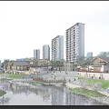 Scenic Commercial Street With River Pedestrians Traditional Modern Buildings Blooming Trees And Flowers