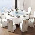 Modern Round Dining Table Set With White Tablecloth Flower Vase And White Surrounding Chairs