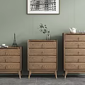 Three Wooden Dressers Against Light Green Wall With Artwork And Decor On Top