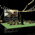 Outdoor Cinema With Yellow String Lights Large Movie Screen Green Carpet Foldable Chairs Potted Plants