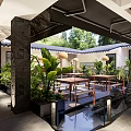 Modern Restaurant Outdoor Courtyard With Green Plants Water Feature And Wooden Tables