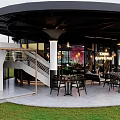Modern Café With Curved Roof Glass Walls Outdoor Seating And Greenery Decor