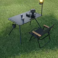 Black Metal Outdoor Table With Portable Stove Cups And Folding Chair On Grass