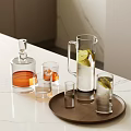 Whiskey Bottle and Glasses with Ice Cubes Pitcher Lemon Slices on Brown Tray White Countertop