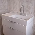 White Bathroom Vanity With Countertop Faucet Knobs Drawers And Patterned Tiled Wall