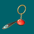 Gold Keychain Pendant With Red Circular Element And Black Peacock Feather Design