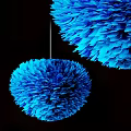 Two Blue Fluffy Feather like Decorative Pendants Hanging Against Black Background