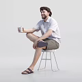 Man sitting on stool holding cup wearing white shirt shorts and sandals against white background