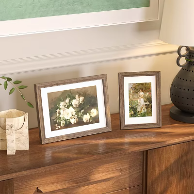 Two Picture Frames with White Flower and Child Art on Wooden Cabinet with Green Plant 3d model