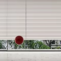 White Venetian Blinds with Red Ball and Green Trees Outside Window