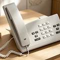 Gray Office Desk Phone With Keypad And Coiled Cord On Wooden Table