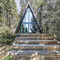 A Frame Detached House with Large Glass Windows in Wooded Forest Setting and Wooden Steps