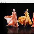 Women Showcasing Flowing Orange Yellow Long Dresses Against Black Background