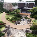 Modern Detached Villa With Glass Walls And Terrace Surrounded By Lush Green Trees And Garden