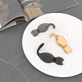 Black and Gold Curved Hooks on White Speckled Plate with Open Magazine and Gray Countertop