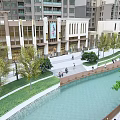 Modern Scenic Waterfront Landscape With Promenade People Walking High Rise Buildings And Green Trees