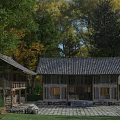 Traditional Wooden House With Tile Roof Surrounded by Autumn Trees and Stone Yard
