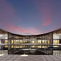 Modern Architectural Building With Curved Wooden Roof And Water Reflection In Evening Sky