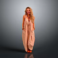 Blonde woman in light brown halter maxi dress with hands in pockets against gray background