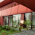 Modern Shopping Mall Store With Red Exterior Large Glass Windows And Green Plants