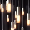 Modern Cylindrical Metallic Pendant Lights with Warm Glowing Light Clustered Against Dark Backdrop