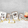 Stylish Photo Check-in Spot With Golden Frames Displaying Newspaper Content And Landscape Art On White Floor