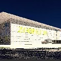 Modern Industrial Factory Building Featuring Glass Curtain Wall Metal Structure And People Under Blue Sky