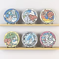 Vibrant Decorative Plates Arranged On Wooden Shelves With Colorful Cartoon Designs
