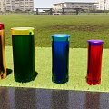 Colorful Cylindrical Musical Instruments and Art Supplies Placed on Grassy Field with Tall Buildings