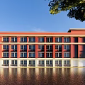 Red Brick School Building With Modern Main Entrance And Water Reflection Surrounding Trees