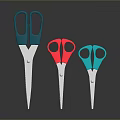 Three Different Colored Scissors with Metal Blades and Colored Handles on Dark Background