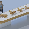 Toy Boy Doll Standing by Table with Four Wooden Airplane Models