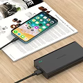 Smartphone Charging with Portable Power Bank on Magazine Over Wooden Table