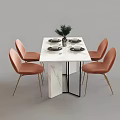 White Dining Table Set With Orange Gold Leg Chairs Vase Green Plant And Black Plates