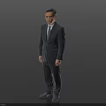 A Man Standing In Dark Background Wearing Gray Suit And Tie