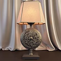 Decorative Table Lamp With Intricate Carved Metallic Base And Fabric Shade Against Velvet Curtains