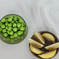 Fresh Green Peas in Glass Bowl with Lemon Slices on Wooden Plate