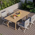Outdoor Wooden Dining Table With Four Gray Chairs And Fruit Bowls Near Green Plants