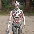 Biomechanical Cyborg With Mechanical Biological Features Holding Weapon In Ruined Urban Setting