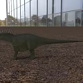Green Dinosaur with Spiked Back Standing on Gravel Ground in Front of Glass Building Background