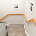 Modern Staircase With Wooden Handrail And Glass Railings Framed Pictures And Yellow Flowers