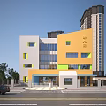 Colorful Kindergarten School Building With Orange White Green Exterior Glass Windows And Trees Near Street