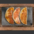 Three Crispy Golden Fried Dumplings on Stone Slab in Wooden Tray