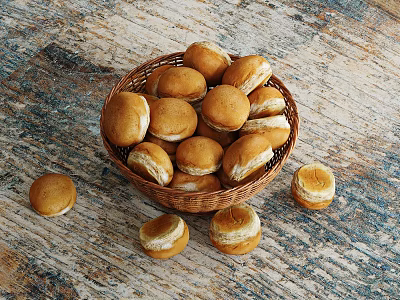 Freshly Baked Small Round Rolls In Wicker Basket On Wooden Tabletop And Scattered Around 3d model