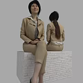 Woman Wearing Beige Suit and Light Shirt Sitting on White Brick Platform with Gray Background
