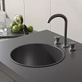 Black Round Kitchen Sink With Silver Faucet Two Handles And Green Fruits On Countertop