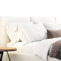 Modern Upholstered Double Bed With White Pillows Striped Blanket And Wooden Side Table