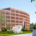 Red Brick School Building With Curved Design Windows Green Lawn White Sculpture And Trees Surroundings