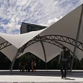 Modern Membrane Canopy With White Fabric Metal Frame Under Cloudy Sky Near Building People Gather