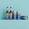 Refreshing Beer Bottles And Cans On Light Blue Background With One Can Tilted